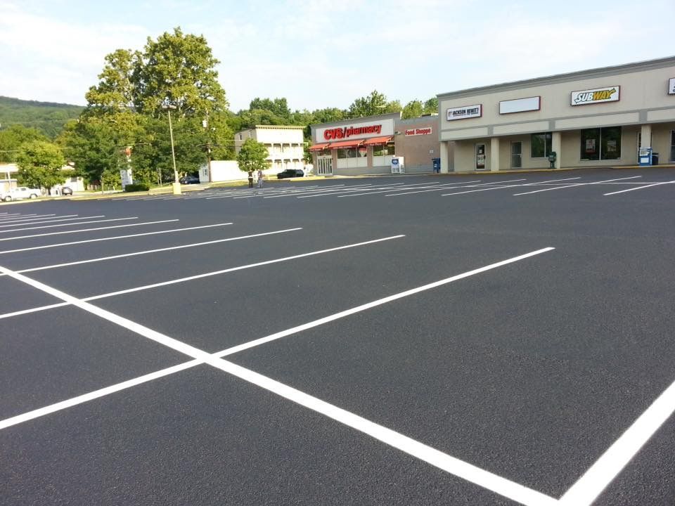 Empty parking lot with fresh white lines beside a row of storefronts and trees
