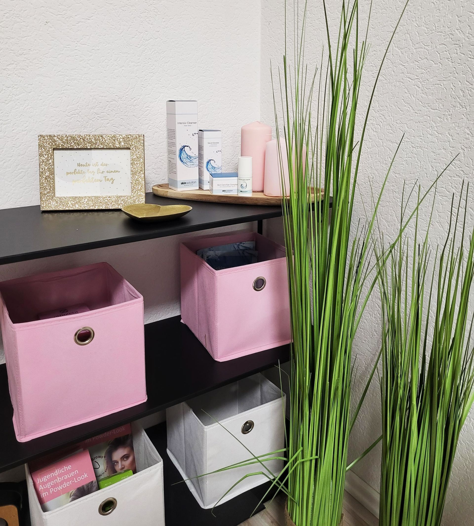 Ein Regal mit rosa und weißen Kisten darauf