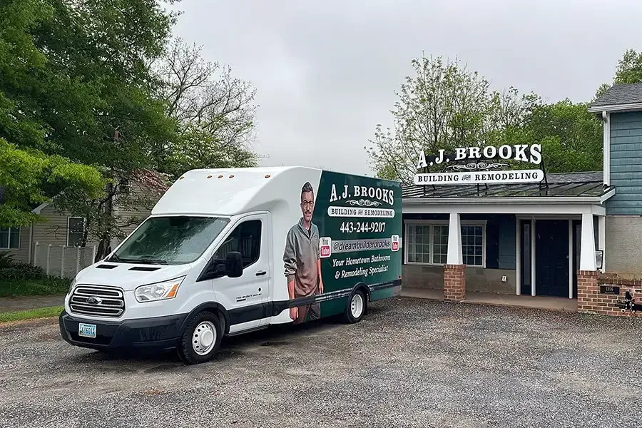 White box truck parked beside J. Brooks building with green landscaping and gravel lot