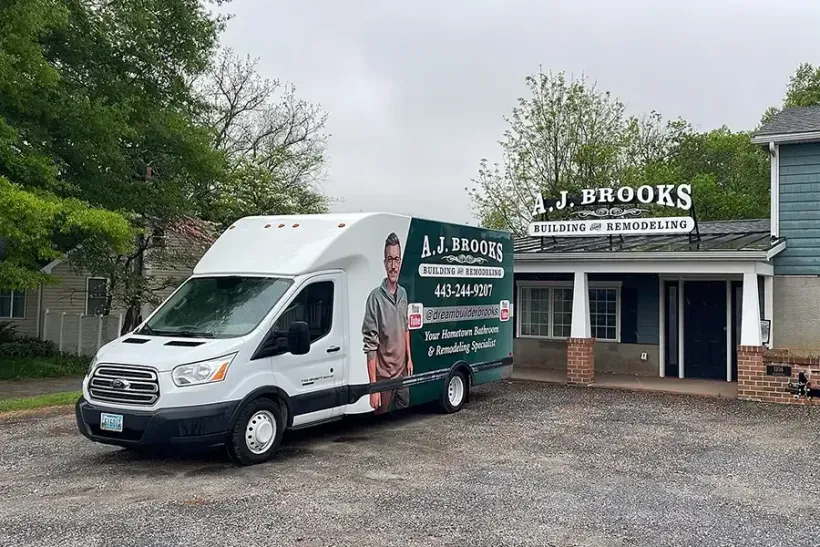 White box truck parked beside J. Brooks building with green landscaping and gravel lot