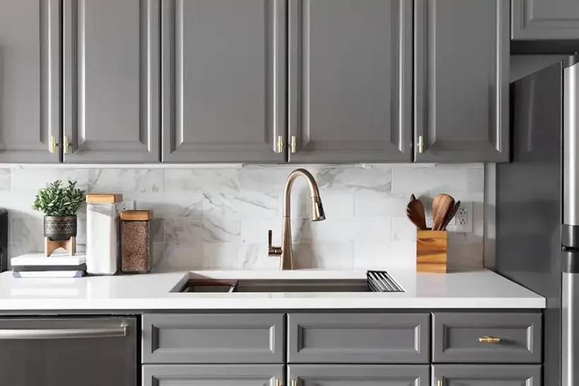 Modern gray kitchen with marble backsplash, white countertop, sink, and stainless steel appliances