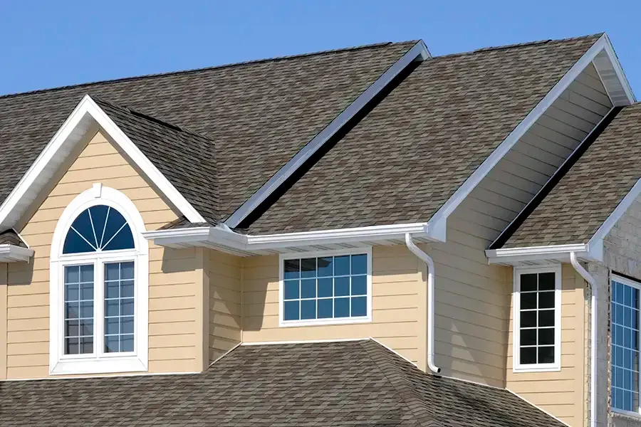 Tan suburban house exterior with beige siding, white trim, and a dark shingled roof