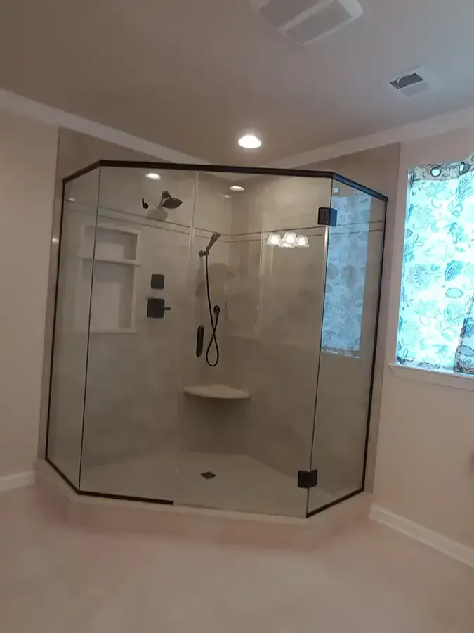 Modern walk-in shower with glass enclosure, white tiled walls, and windowed bathroom interior