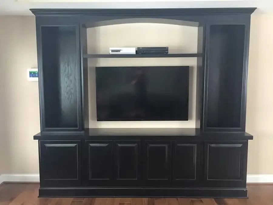 Black entertainment center with a TV and shelf in a living room.