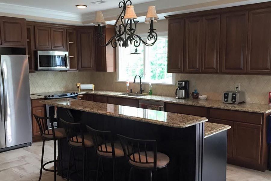 Modern kitchen with dark wood cabinets, stainless appliances, and a large island with bar stools