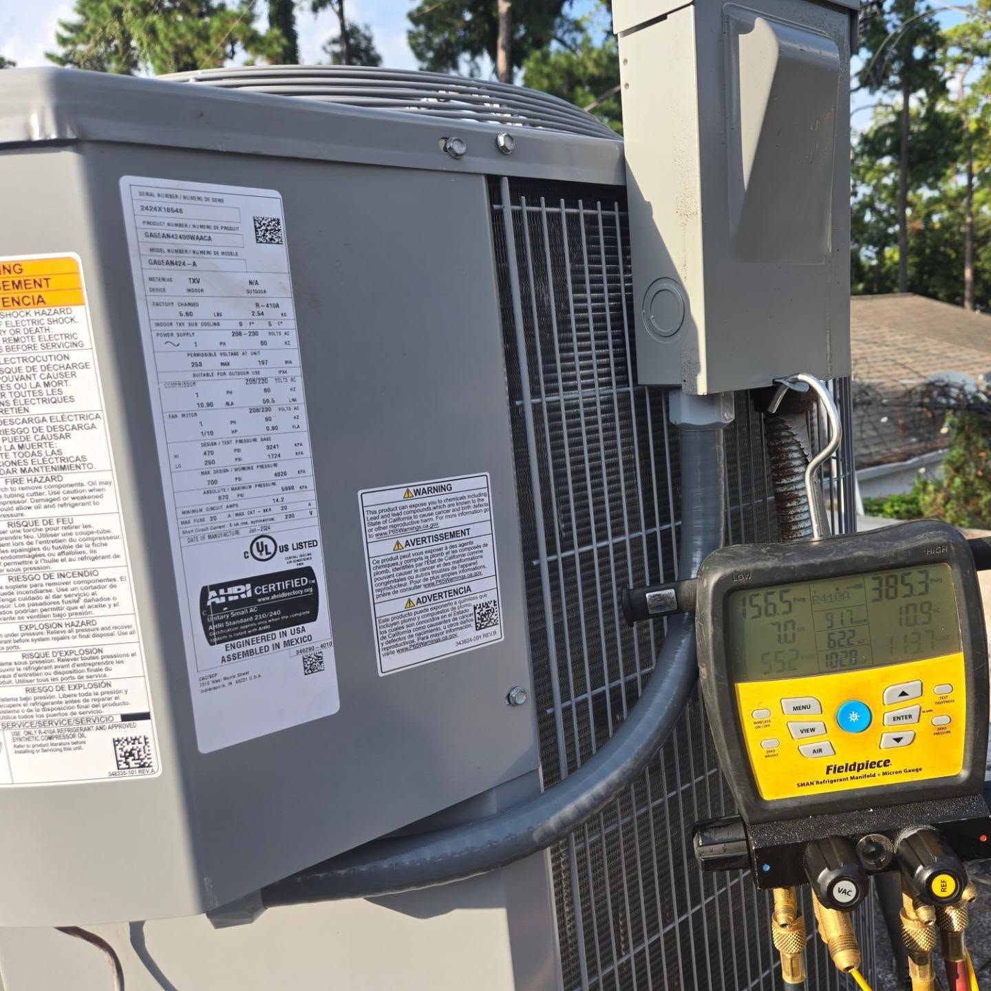 HVAC outdoor unit with attached yellow manifold gauges and service hoses outdoors