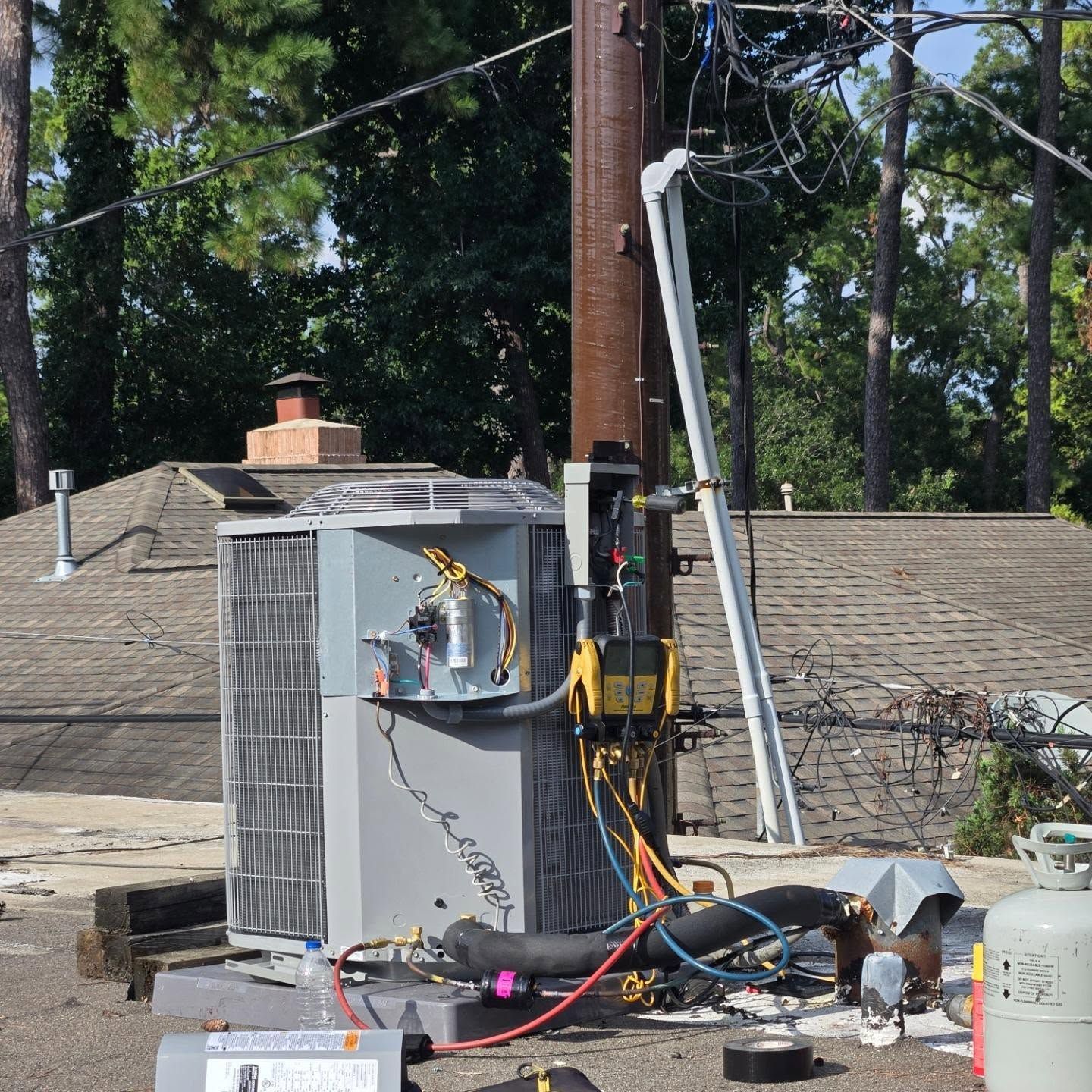 Outdoor HVAC unit and service equipment beside a utility pole on a roof or flat surface.