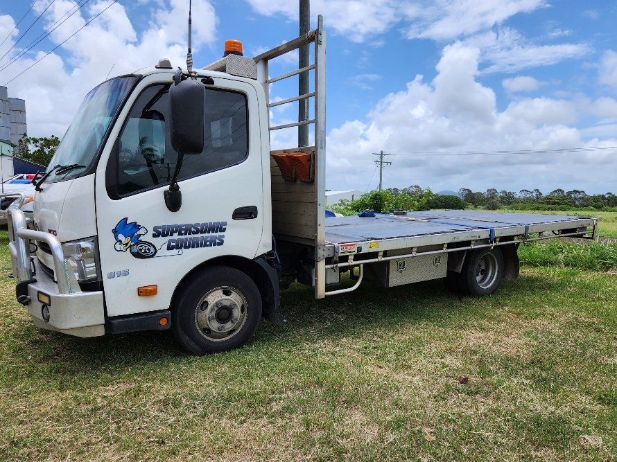 A White Tow Truck is Parked in a Grassy Field — Supersonic Couriers In West Mackay, QLD