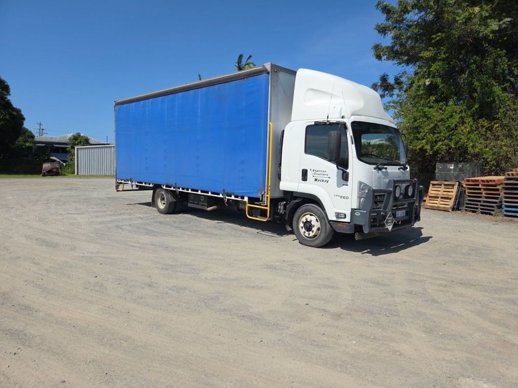 A Tow Truck is Carrying a Row of Vans on a Trailer — Supersonic Couriers In West Mackay, QLD