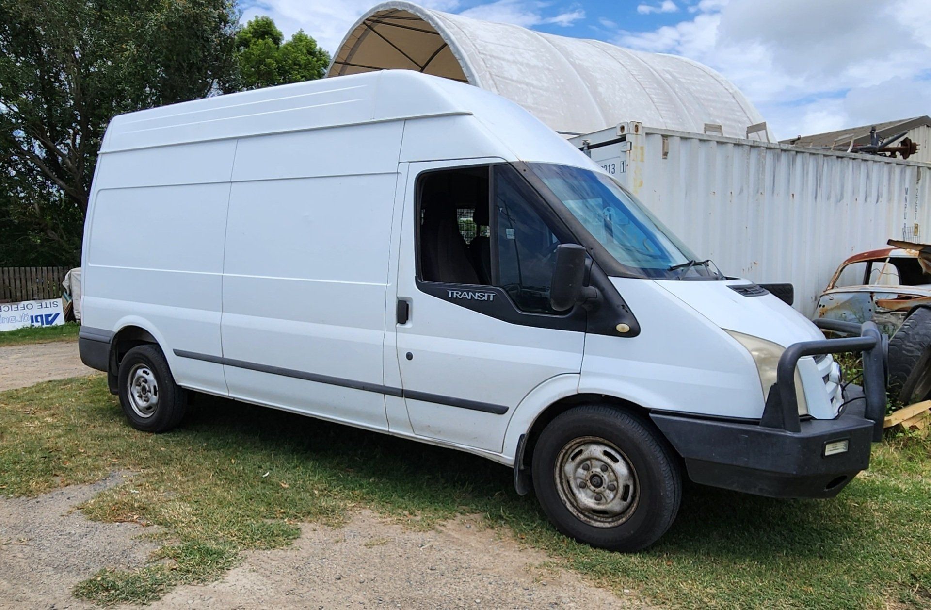 A White Van is Parked in a Grassy Area in Front of a Building — Supersonic Couriers In West Mackay, QLD