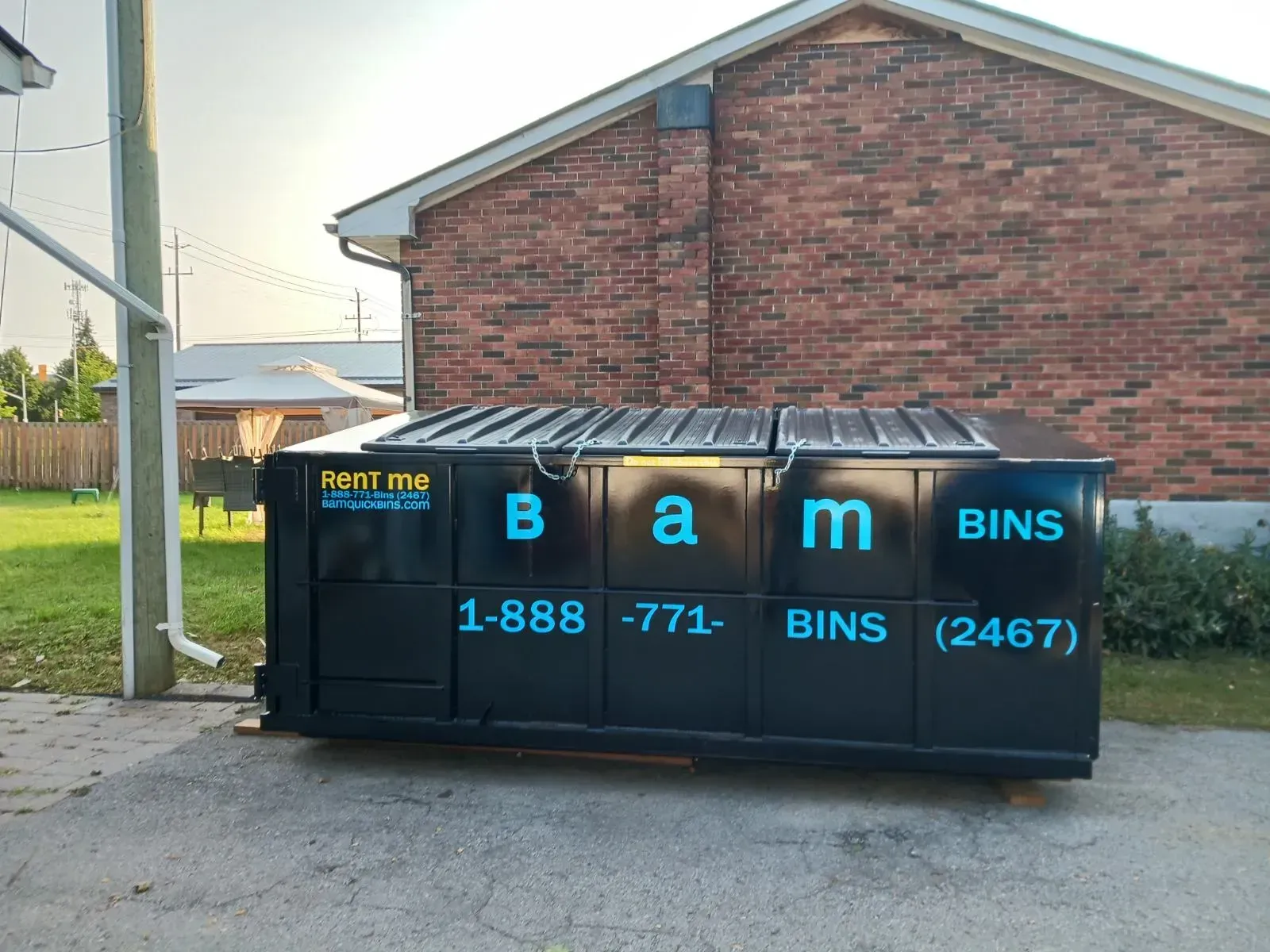 Black dumpster with teal text reading 