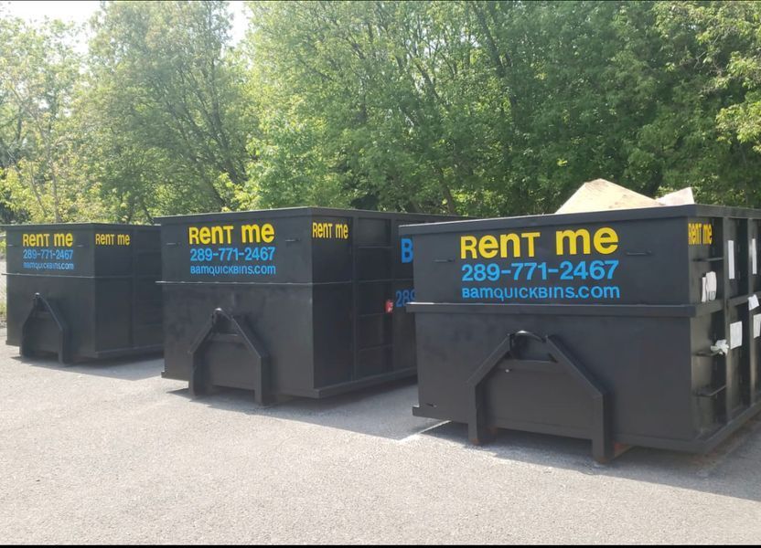 Three black dumpsters with 