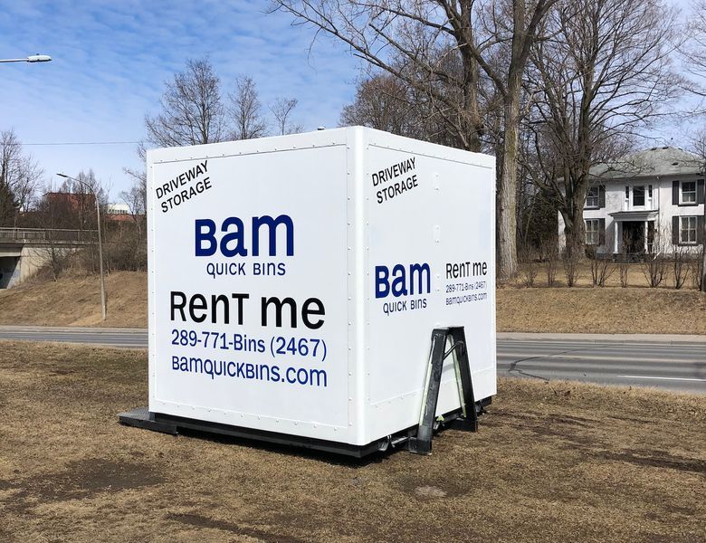White BAM Quick Bins storage container on a grassy area, advertising 