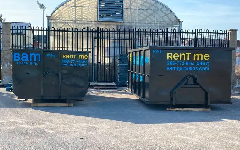 Two dark dumpsters labeled 