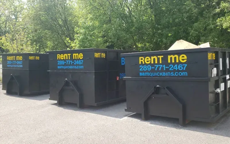 Three black dumpsters with 