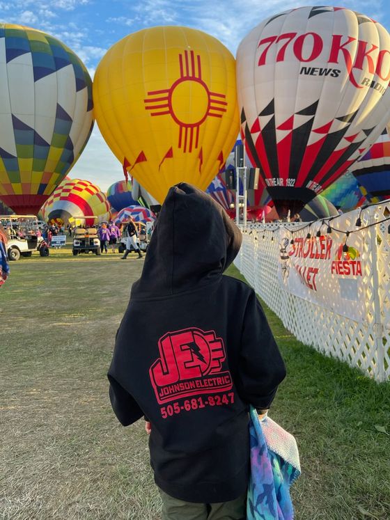 A child is standing in front of a bunch of hot air balloons