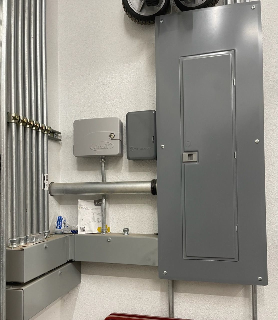 A gray electrical box is hanging on a white wall.