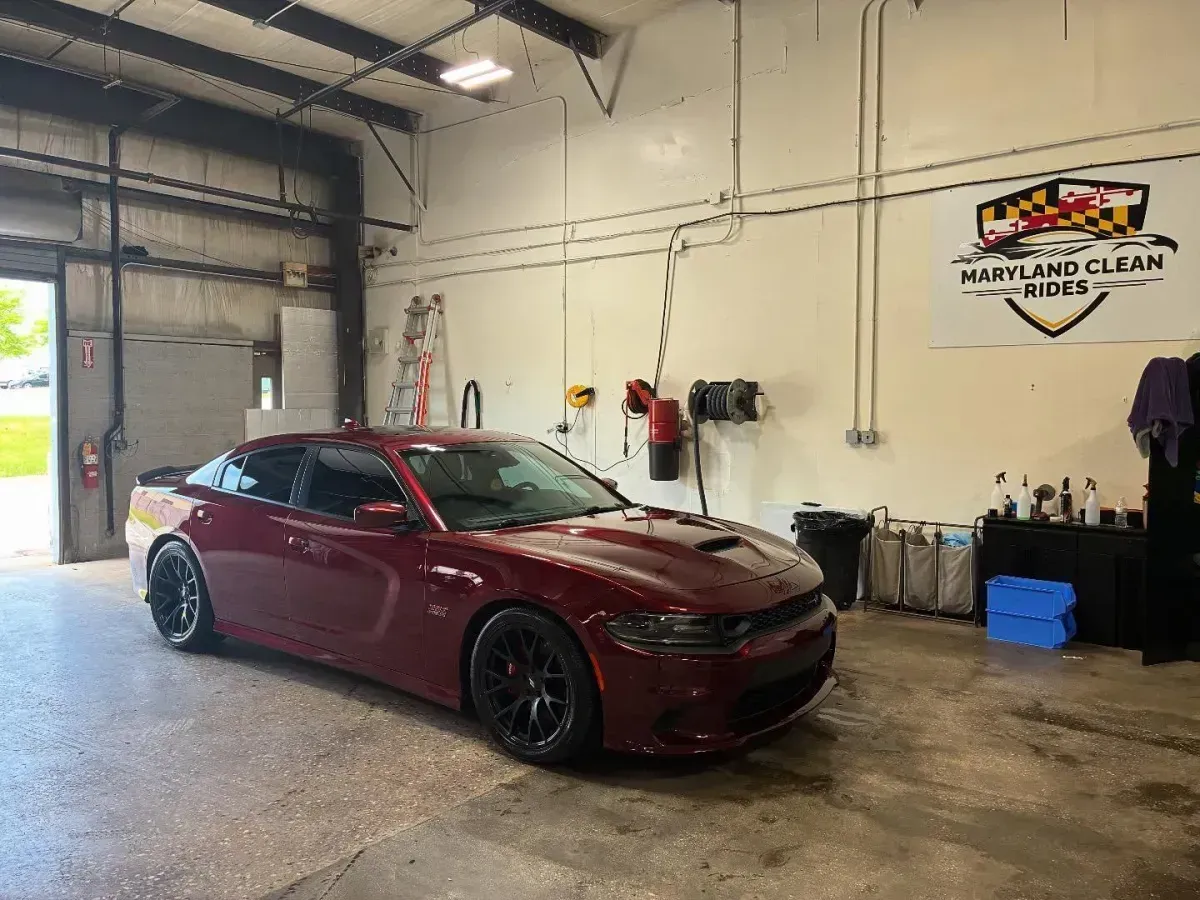 Maroon Dodge Charger inside a car wash bay.