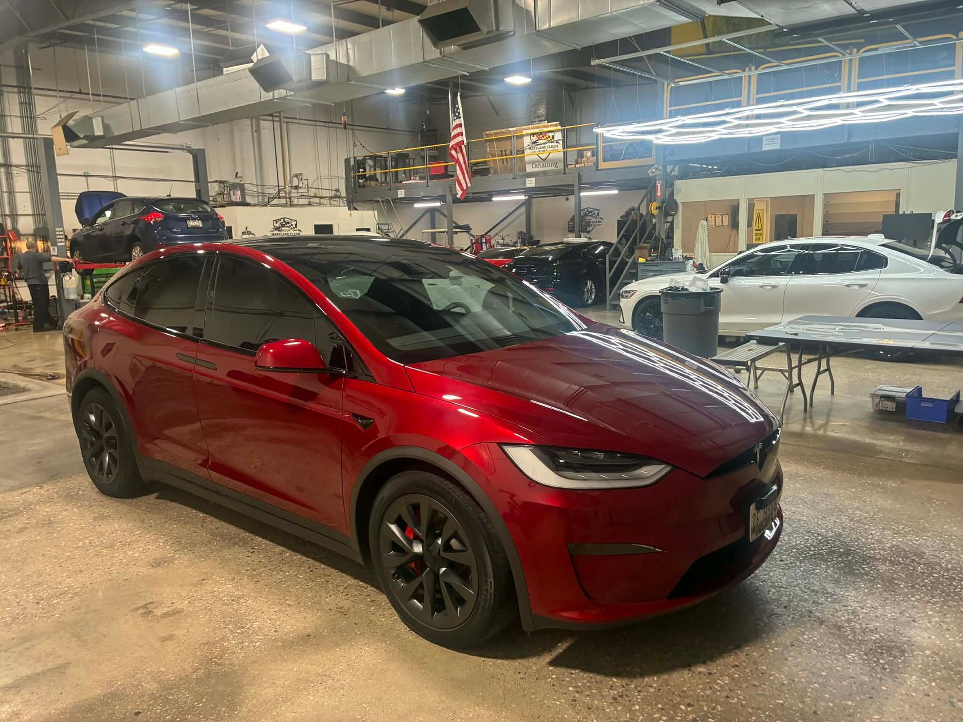 Red Tesla SUV in a garage, black wheels, tinted windows.