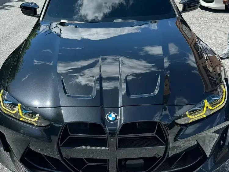 Black BMW car with a custom hood and yellow accented headlights.