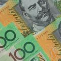 Close-up of Australian 100-dollar banknotes with green and orange designs and a portrait
