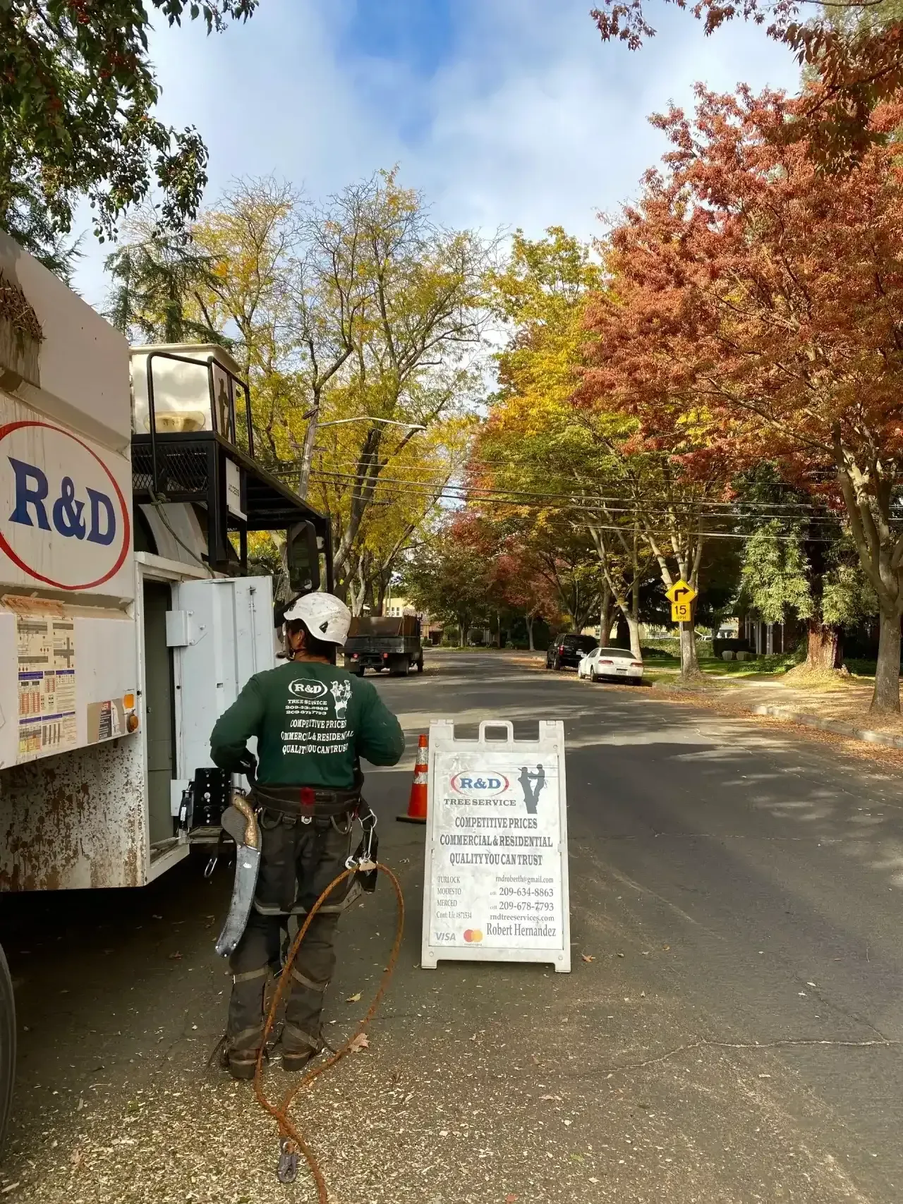 Person with bicycle stands by roadside sign near a truck under autumn trees