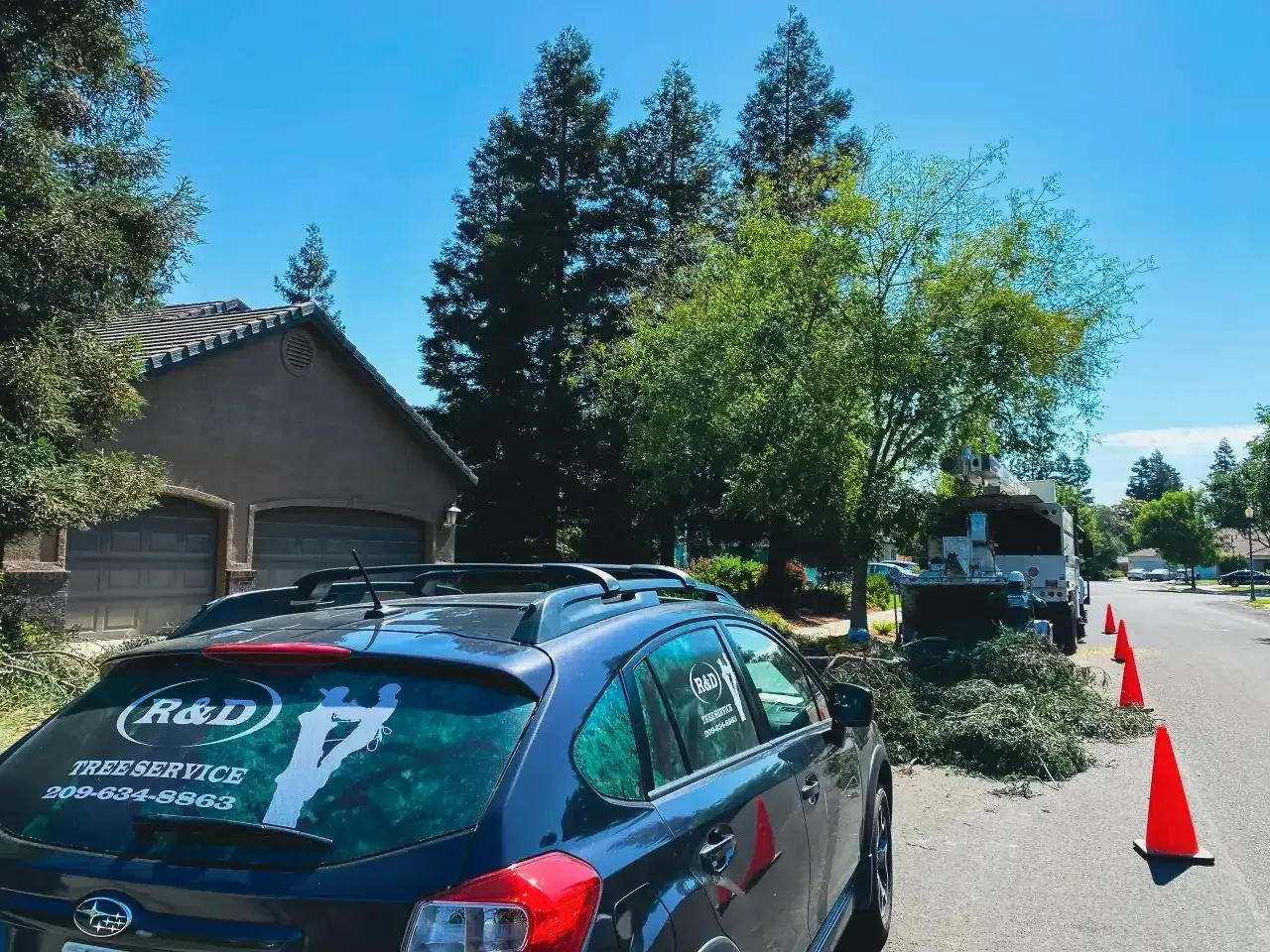 Parked dark blue SUV with roof boxes near orange cones on a sunny suburban street
