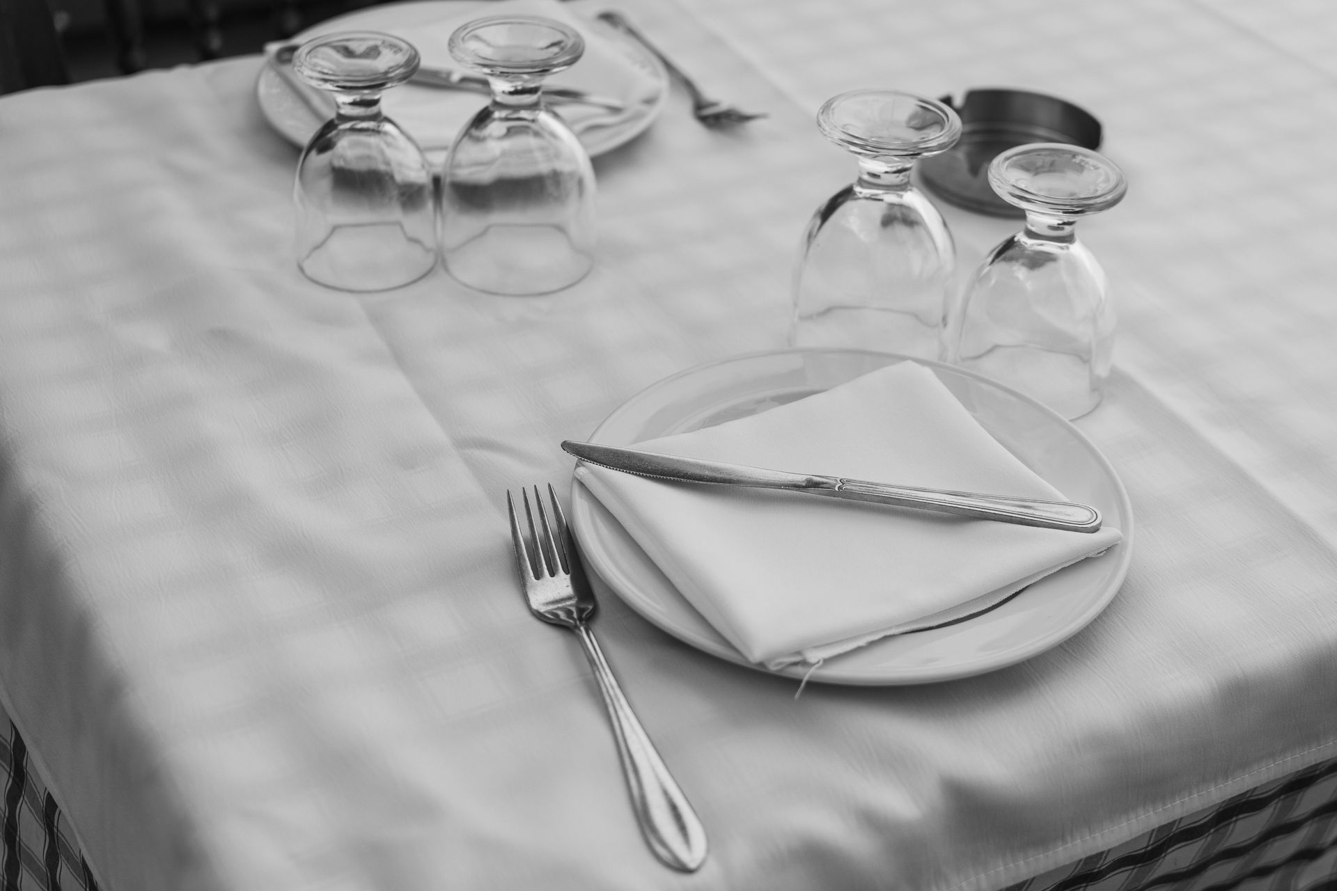 Table setting with folded napkins, upside-down glasses, and silverware on a checkered tablecloth