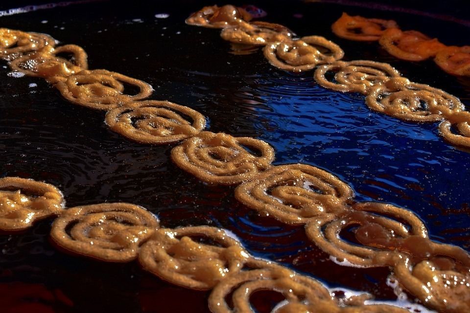 Jalebi pastries frying in hot oil, golden brown swirls.