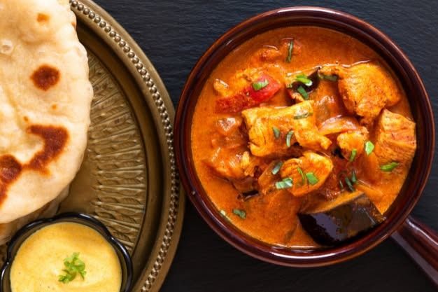 Indian curry dish with naan bread and dipping sauce.