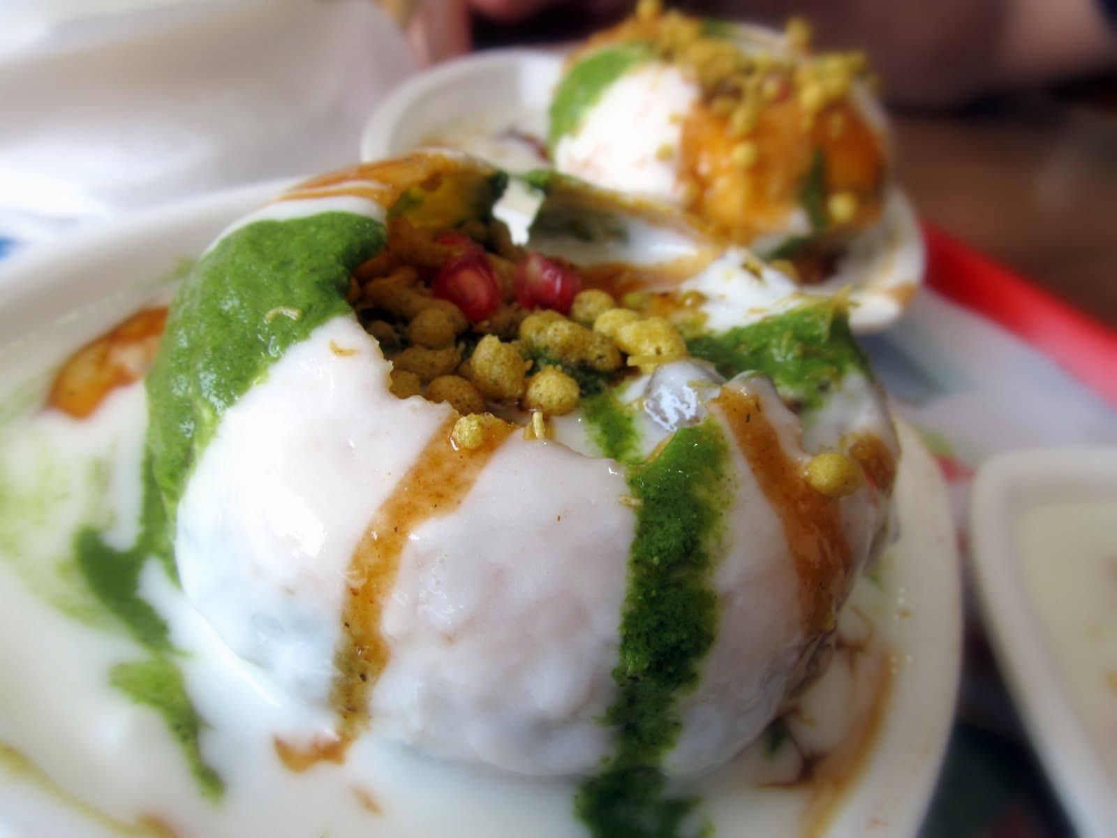 Dahi puri: Deep-fried, puffed bread balls filled with yogurt, chutneys, and savory toppings, served on a plate.