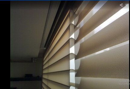 Moderna sala de conferencias con mesa de madera, sillas marrones, paredes de cristal y televisor montado en la pared.