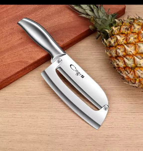 Cuchillo plateado para cortar piña junto a una piña sobre una tabla de cortar de madera.