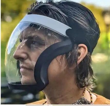 Persona con una careta transparente al aire libre, de perfil, con expresión seria.