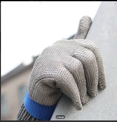 Guante de trabajo de punto gris sujetando una superficie metálica, con el puño azul visible.