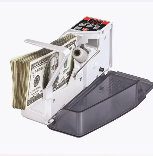 Contador automático de billetes con una pila de billetes estadounidenses y una bandeja gris abierta sobre un fondo blanco.