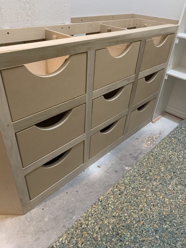 Beige wall-mounted drawer unit with open cubbies in a hallway or entryway.