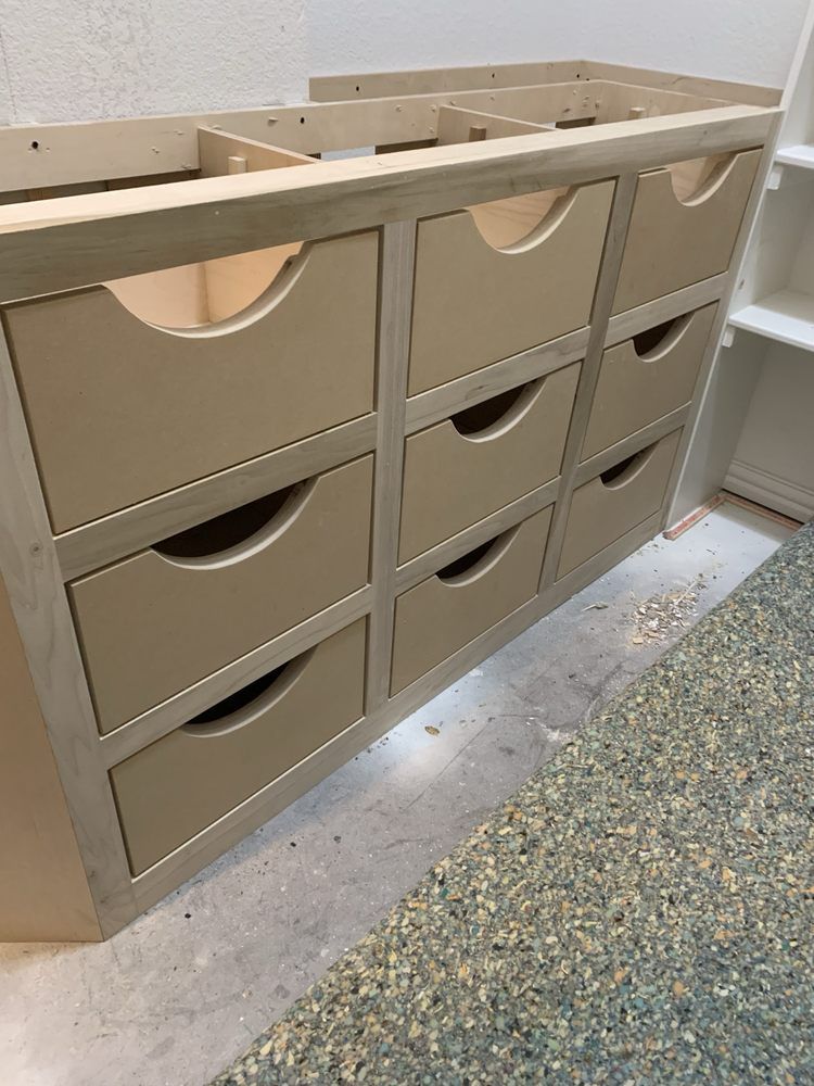 Beige wooden cubby cabinet with pull-out drawers in a storage room