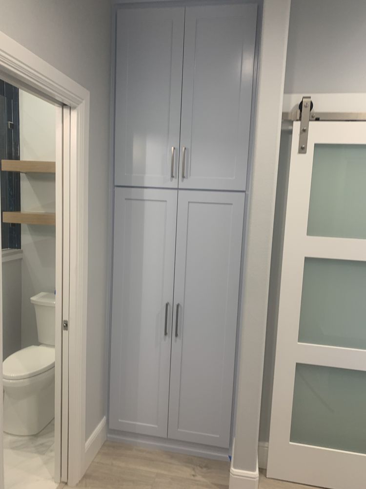 Built-in gray cabinet beside a bathroom doorway and frosted-glass sliding door