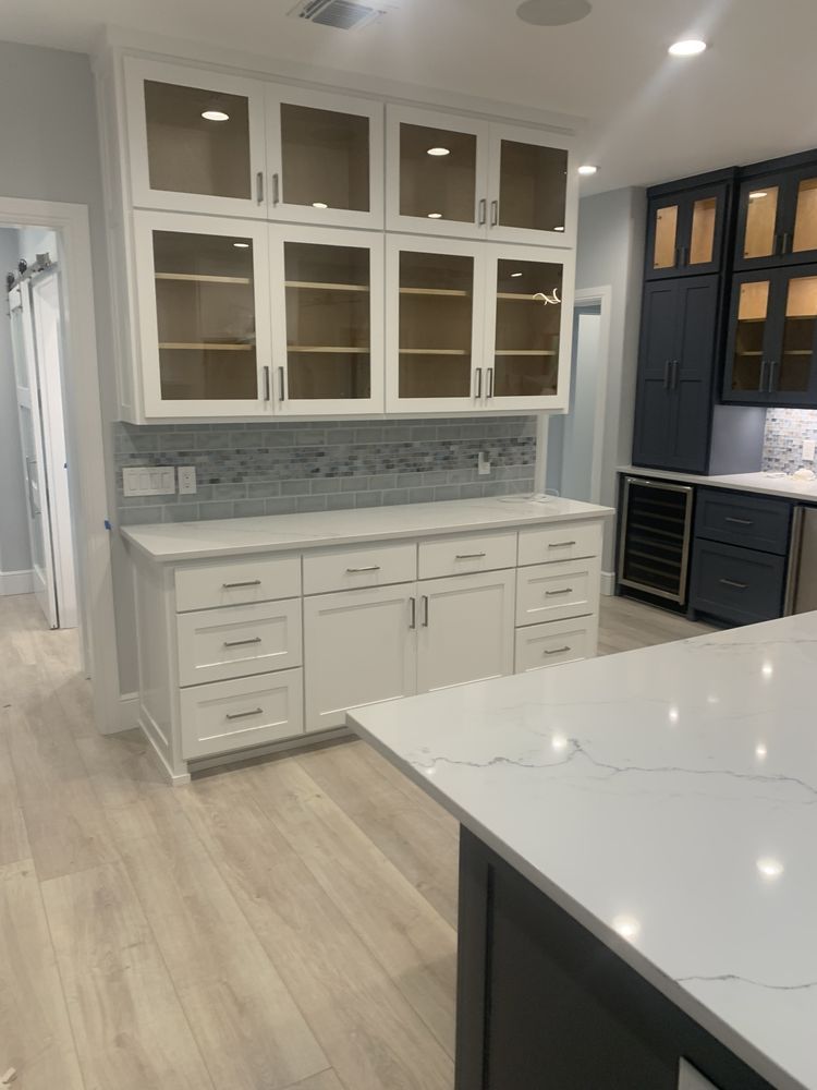 Modern kitchen with white cabinets, gray backsplash, and a marble island countertop