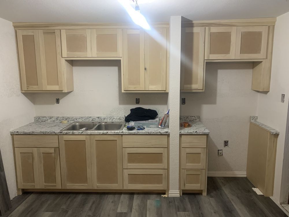 Unfinished kitchen with light wood cabinets, granite countertop, and exposed wall sections on the right.