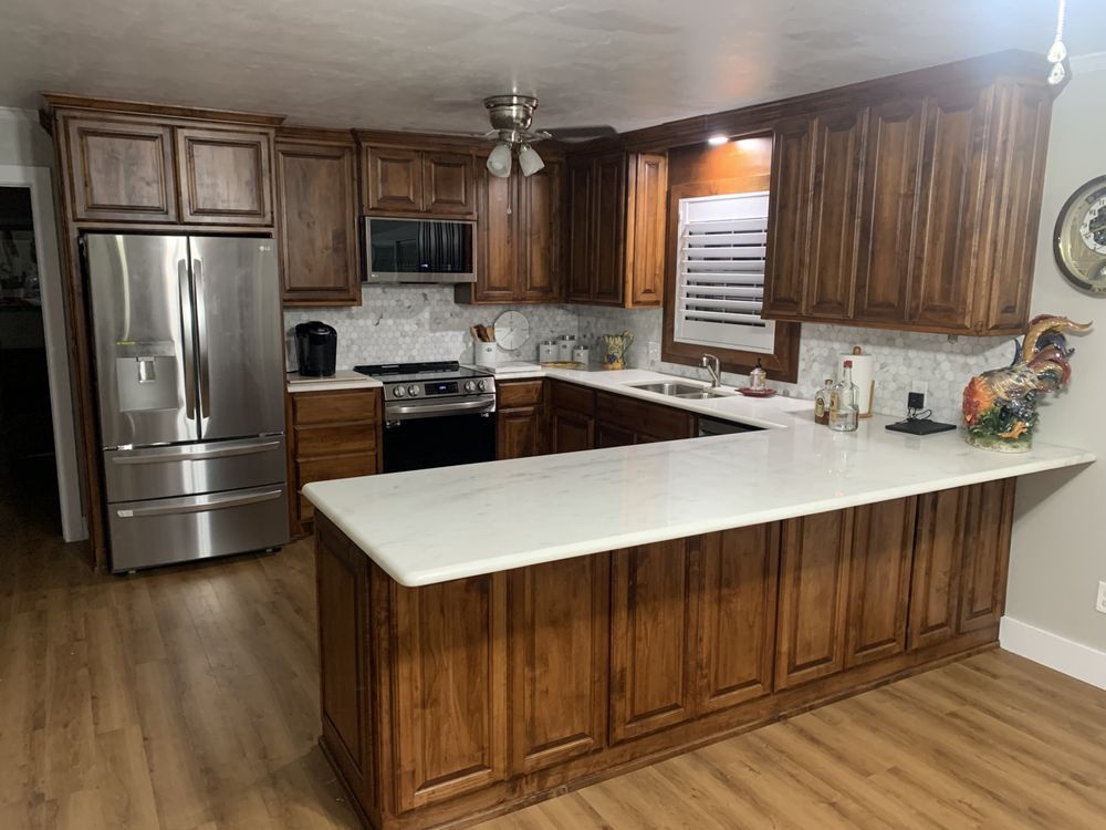 Modern kitchen with wooden cabinets, stainless steel appliances, white countertops, and a large island.