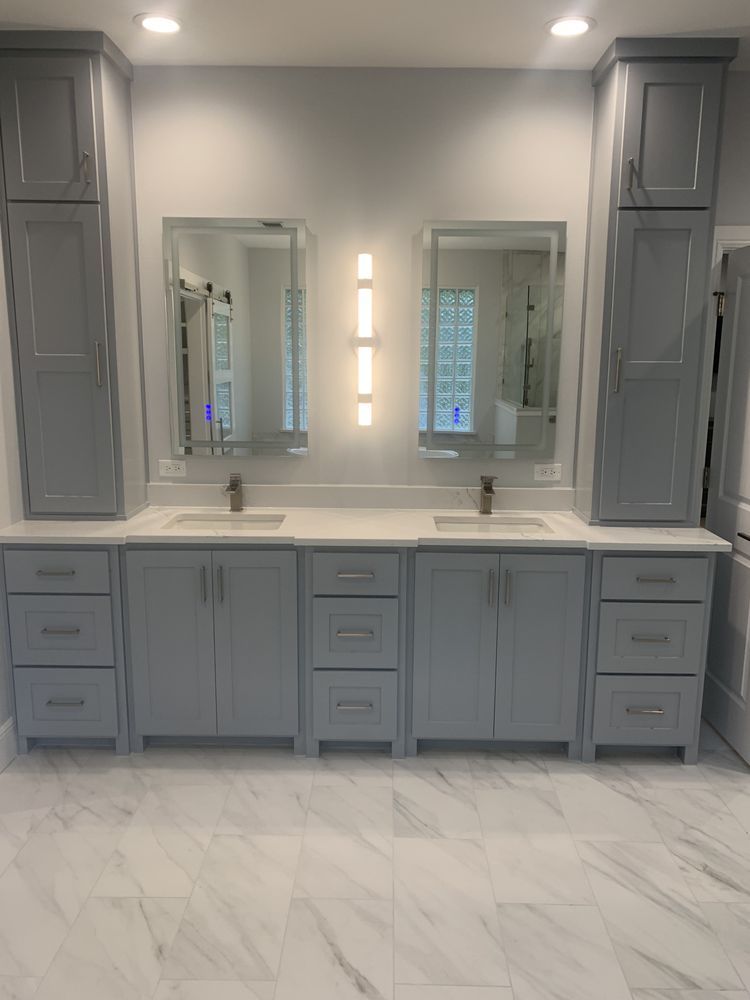 Modern double-sink bathroom vanity with gray cabinets, mirrors, and marble tile floor