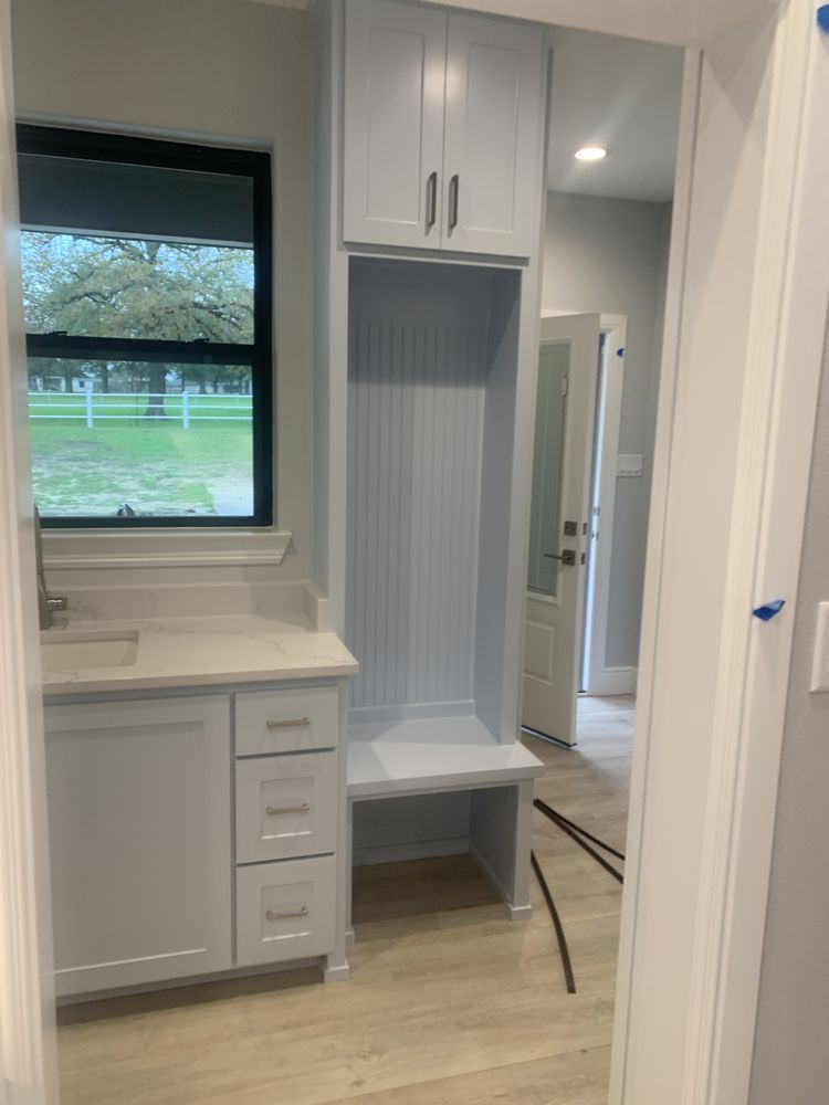 Small white laundry nook with cabinet, countertop, window, and built-in bench seat alcove