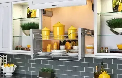 Modern kitchen with open shelving, yellow canisters, glassware, and green plants over a gray tile backsplash