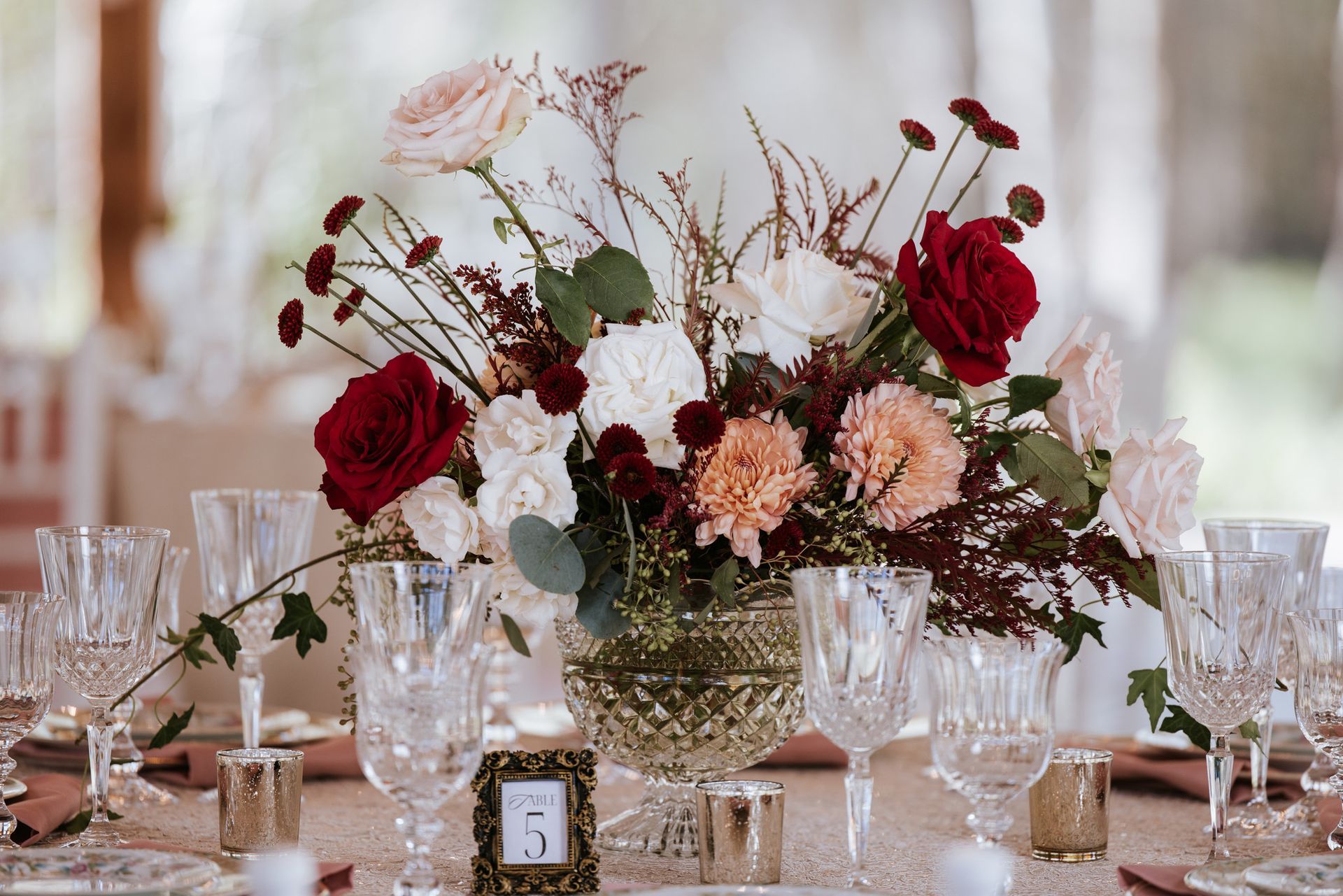 Elegant floral centerpiece with red and blush roses on a decorated dining table