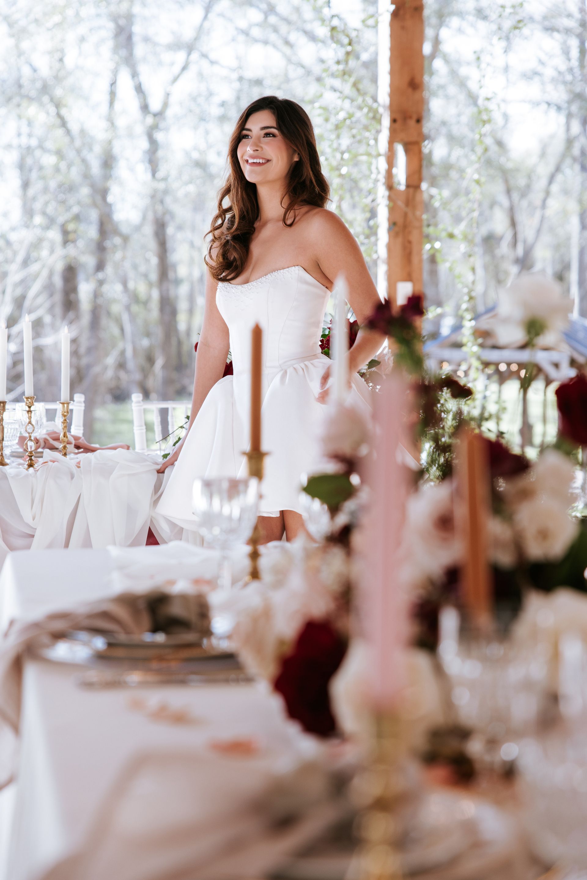 Woman in a white dress standing at a decorated outdoor wedding reception table