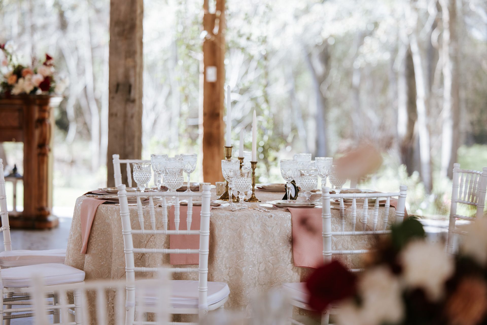 Elegant outdoor wedding reception with white chairs, floral centerpieces, and soft natural light