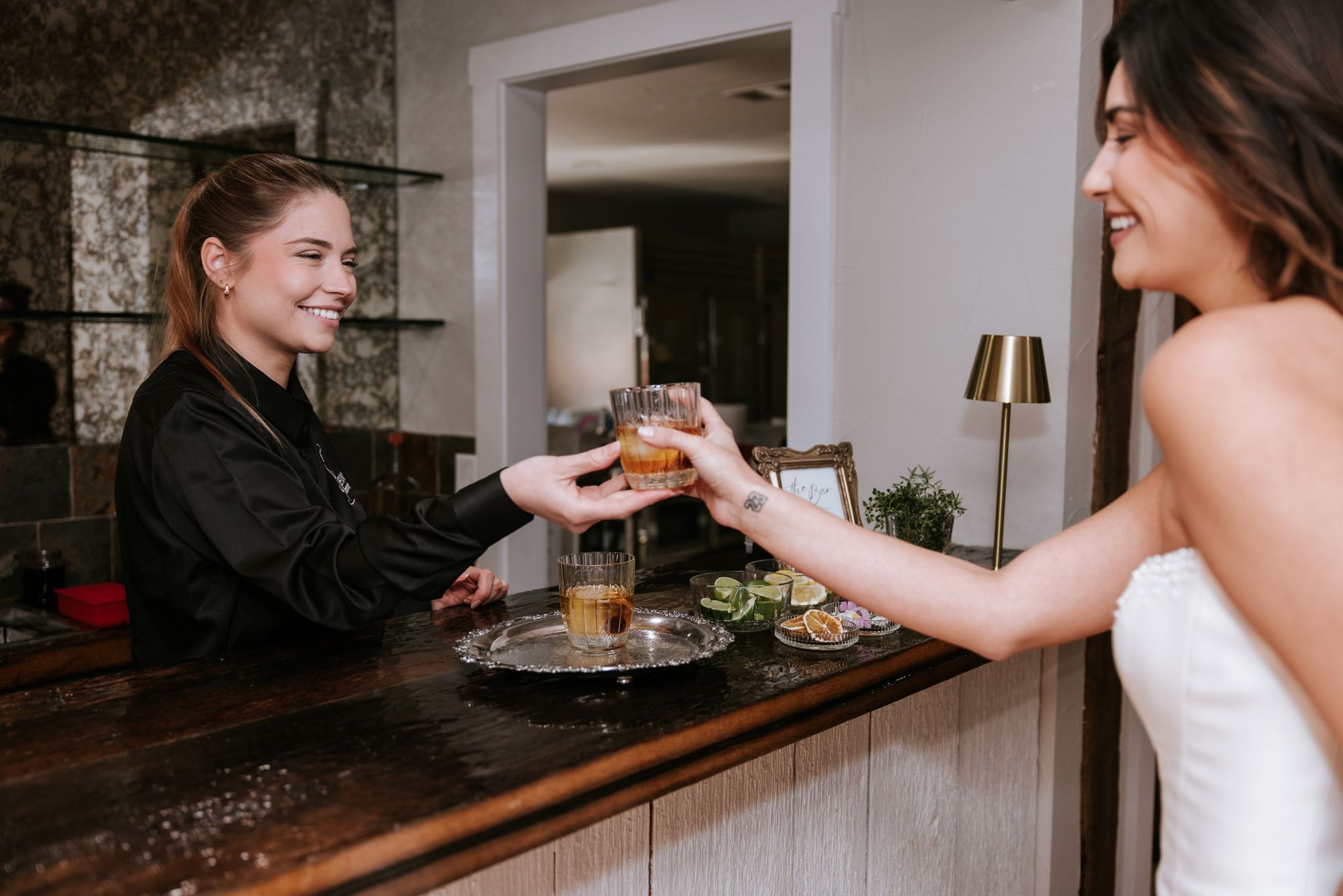 Woman serving a drink to a smiling guest across a bar counter