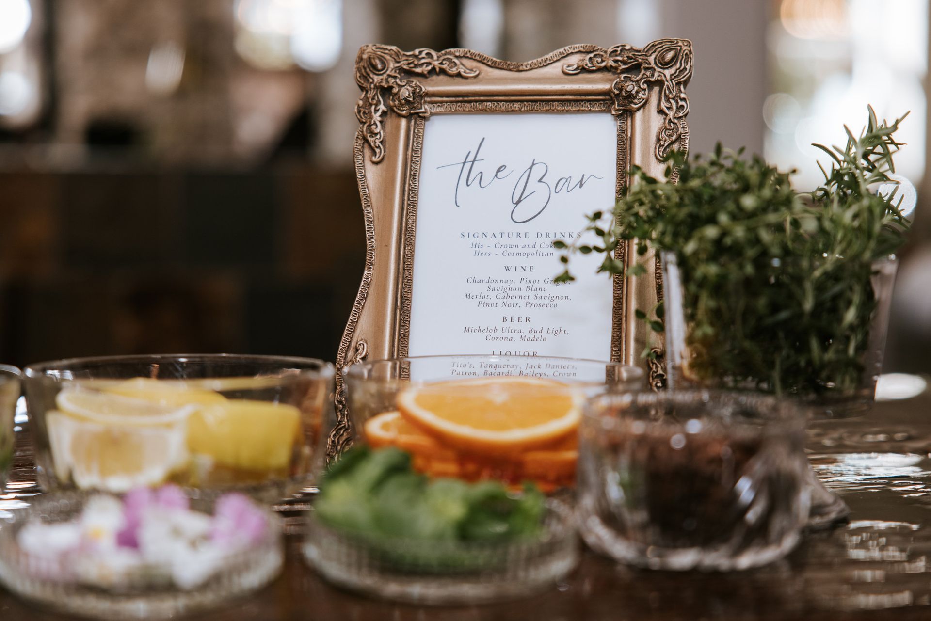 Decorated table with framed sign, citrus slices, glasses, and greenery in a warm indoor setting